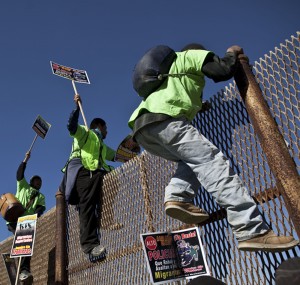 Deported migrants climb a fence at the U.S.- Mexico border as they prepare for the 6th annual Marcha Migrante, or Migrant March in Tijuana, Mexico, Wednesday Feb. 2, 2011. The Tijuana to Mexicali pilgrimage is organized by the group Border Angels to raise awareness on immigration issues. Marchers are demanding a stop of nighttime deportations and human rights abuses by police on both sides of the border. (AP Photo/Guillermo Arias)